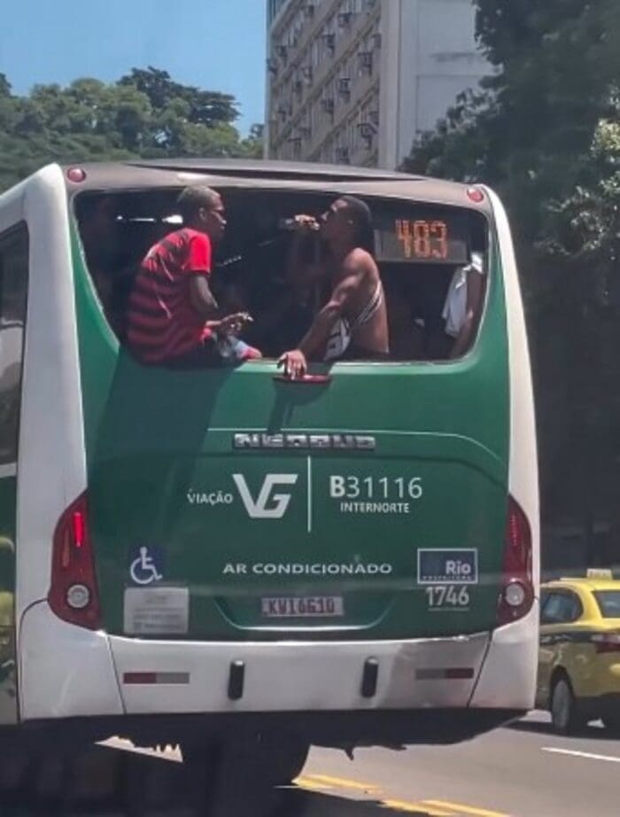 Dois homens ficam sentados em janela sem vidro em ônibus do Rio de Janeiro