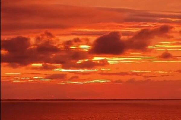 Pôr do sol vibrante sobre a Lagoa de Araruama, com céu alaranjado e nuvens
