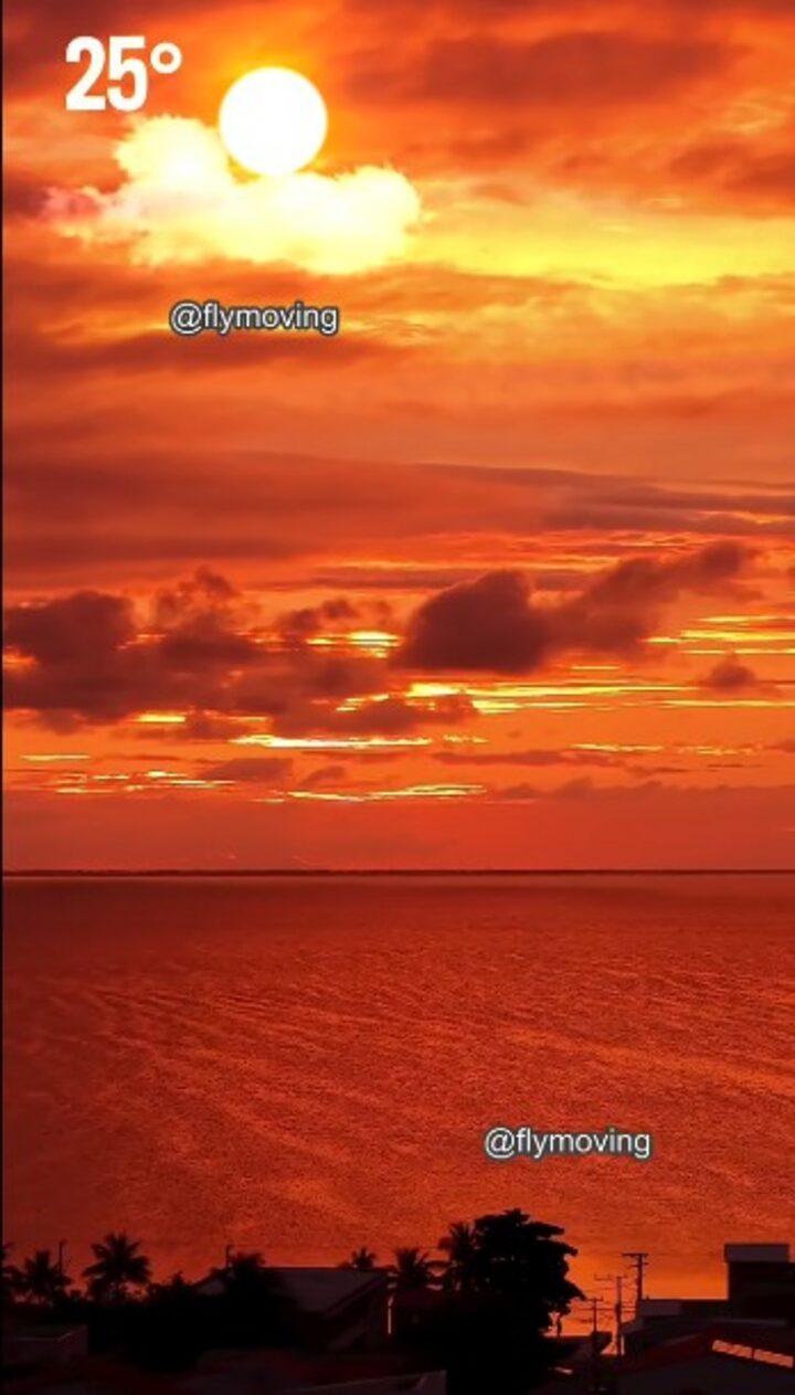 Pôr do sol vibrante sobre a Lagoa de Araruama, com céu alaranjado e nuvens