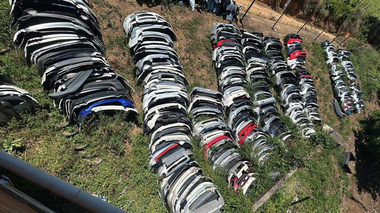 Acervo de para-choques automotivos empilhados em ferro-velho, apreendidos em operação de desmonte.