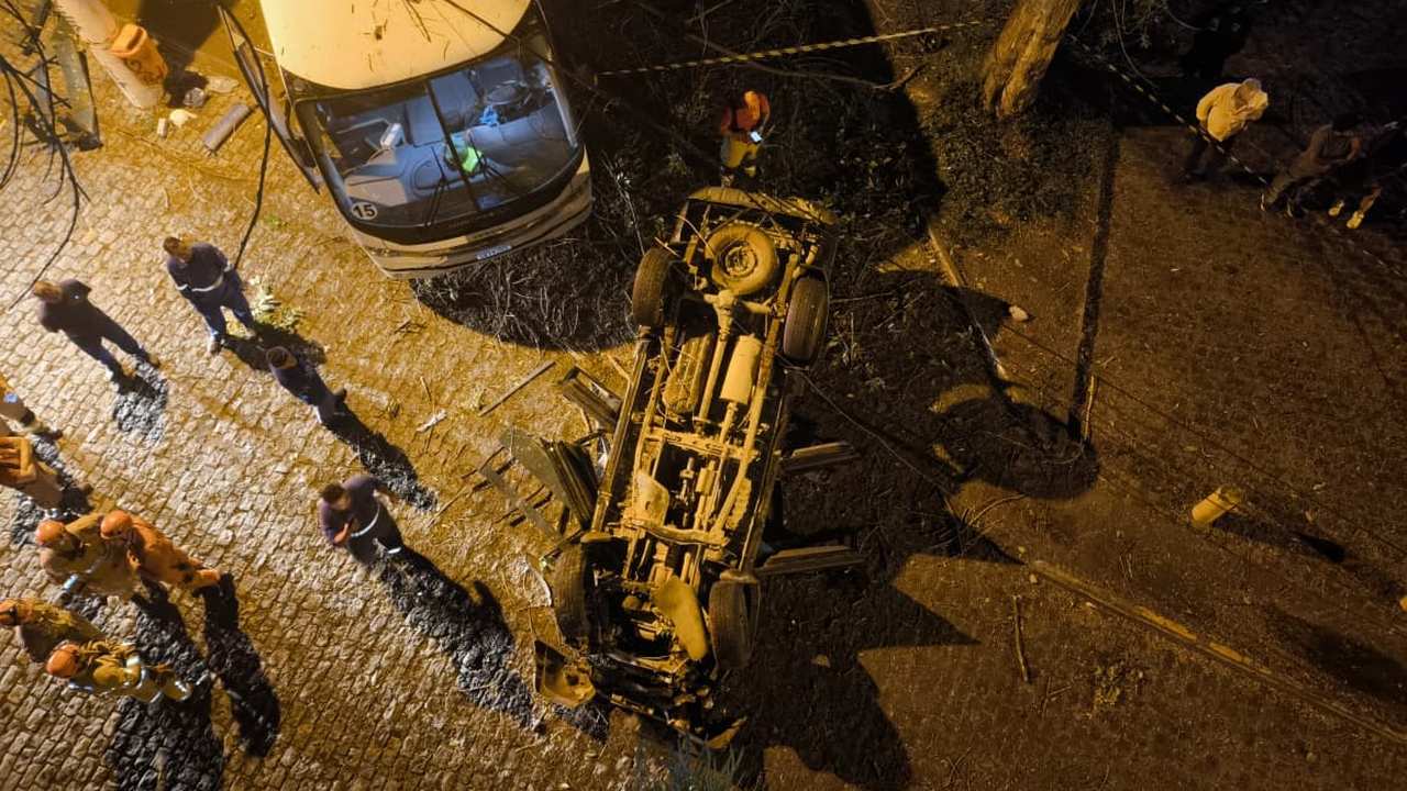 Acidente de carro em viaduto com veículo capotado e equipes de resgate no local.