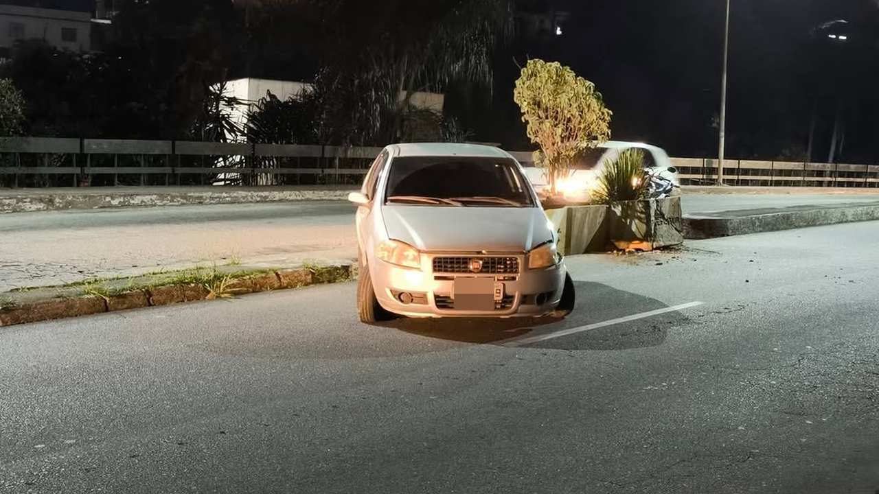 Acidente de carro em viaduto: Fiat Siena danificado após colisão contra jardineira.