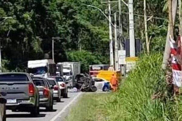 Acidente de trânsito na RJ-130 em Nova Friburgo: carro destruído e fila de veículos.
