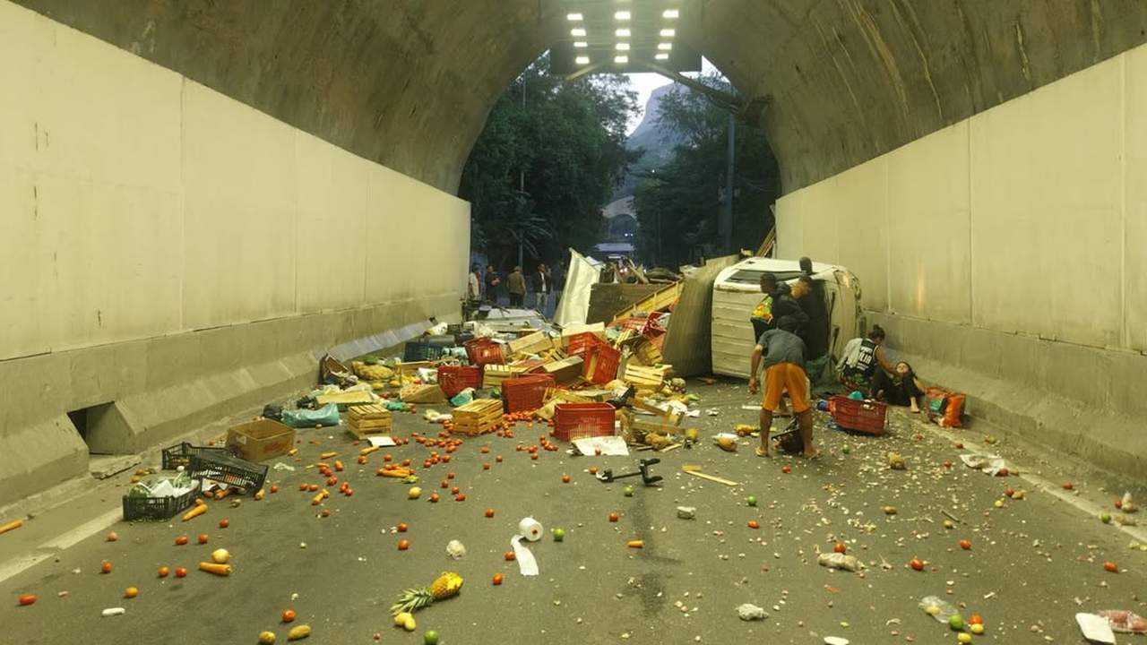 Acidente no Túnel Zuzu Angel: Caminhão tombado com carga de frutas espalhada.