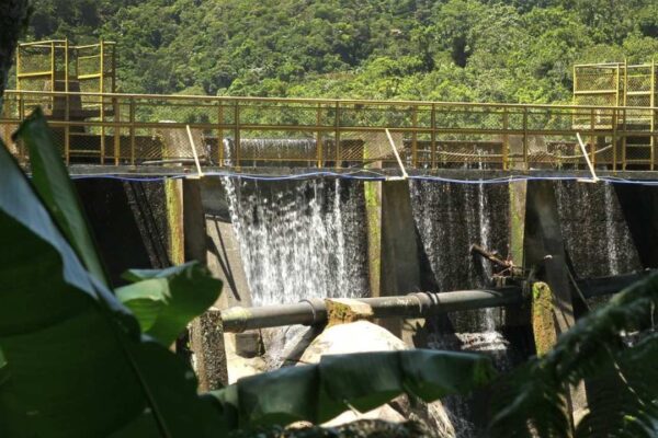 Águas de Nova Friburgo, barragem com água corrente e vegetação ao fundo.