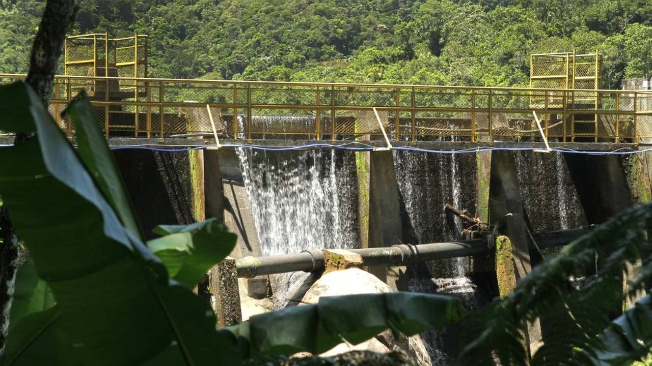 Águas de Nova Friburgo, barragem com água corrente e vegetação ao fundo.