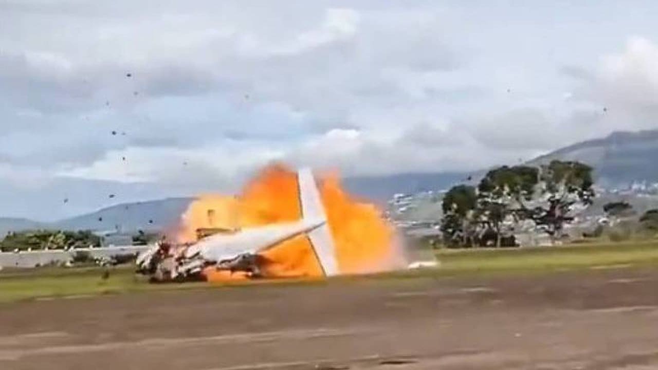 Avião em chamas após queda na Venezuela, mostrando fumaça e destroços.