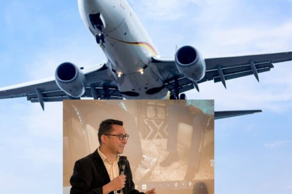 Avião sobrevoando e prefeito Johnny Maycon discursando em evento.