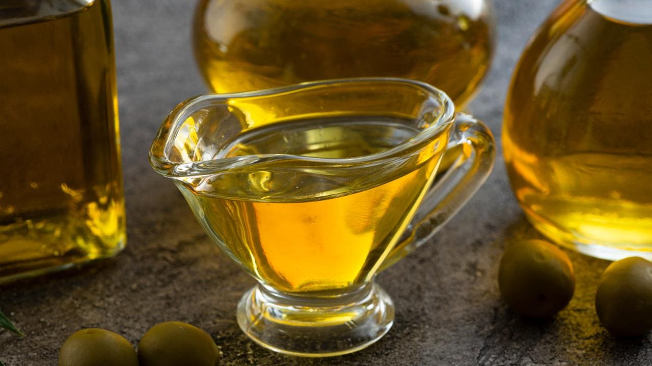 Azeite em recipiente de vidro, com azeitonas.