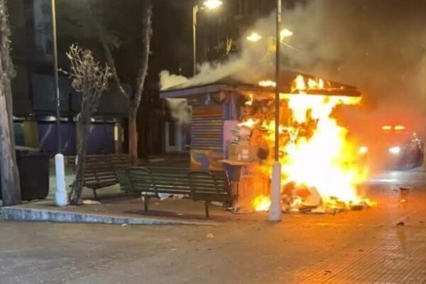 Banca de jornal em chamas durante a noite.