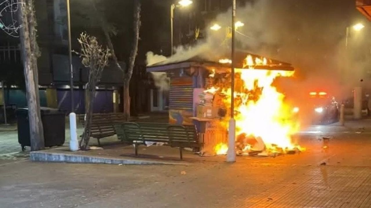 Banca de jornal em chamas durante a noite.