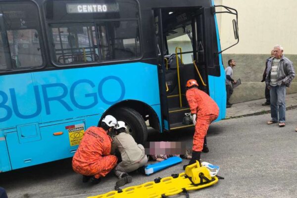 Bombeiros socorrem vítima de atropelamento em Nova Friburgo, próximo a ônibus azul.