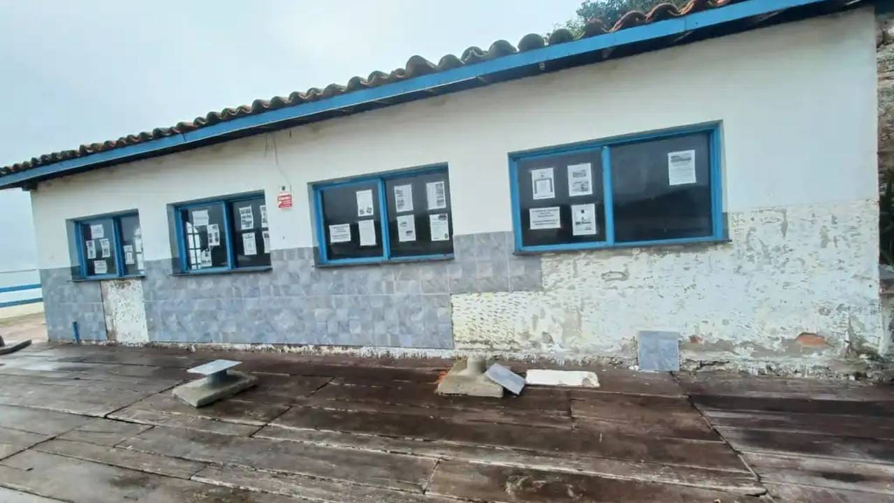 Cabana do Pescador em ruínas com janelas e avisos, local em disputa judicial.
