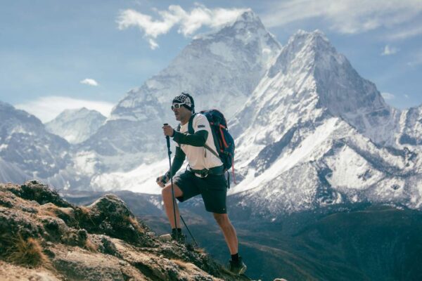 Caminhante escalando montanha nevada com bastões e mochila, em expedição ao Everest.