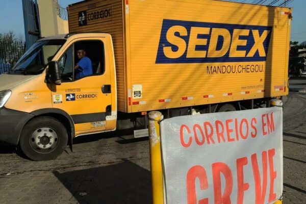 Caminhão dos Correios com a palavra SEDEX em destaque e aviso de greve.