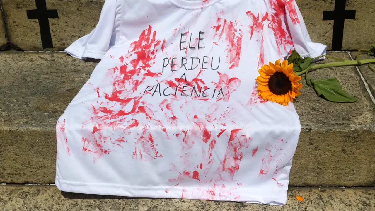Camiseta branca manchada de vermelho com dizeres em protesto contra feminicídio.