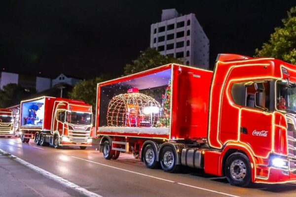 Caravana de Natal da Coca-Cola com caminhões iluminados desfilando à noite
