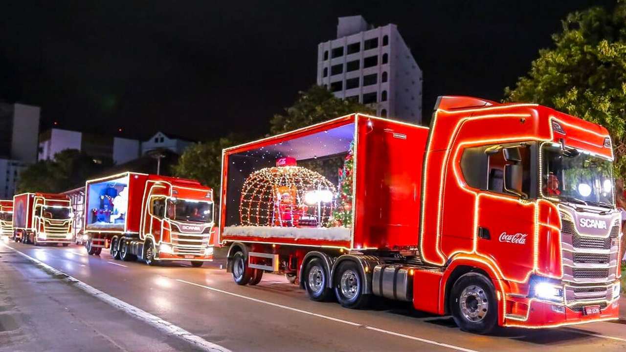 Caravana de Natal da Coca-Cola com caminhões iluminados desfilando à noite