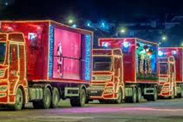 Caravana de Natal da Coca-Cola com caminhões iluminados percorrendo as ruas.