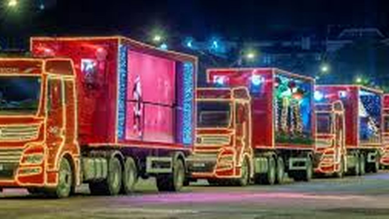 Caravana de Natal da Coca-Cola com caminhões iluminados percorrendo as ruas.