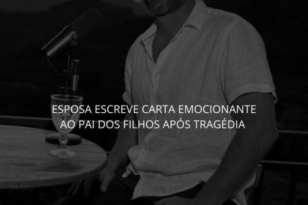 Carlinhos Uruguai, em uma foto em preto e branco, sentado em uma mesa, olhando para a câmera, com um microfone na frente dele.