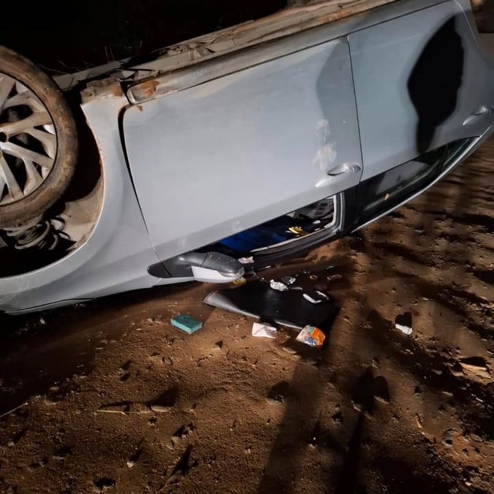 Carro capotado em acidente, com marcas de colisão.