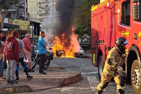 Carro em chamas com bombeiro e caminhão de bombeiros em cena, Nova Friburgo.