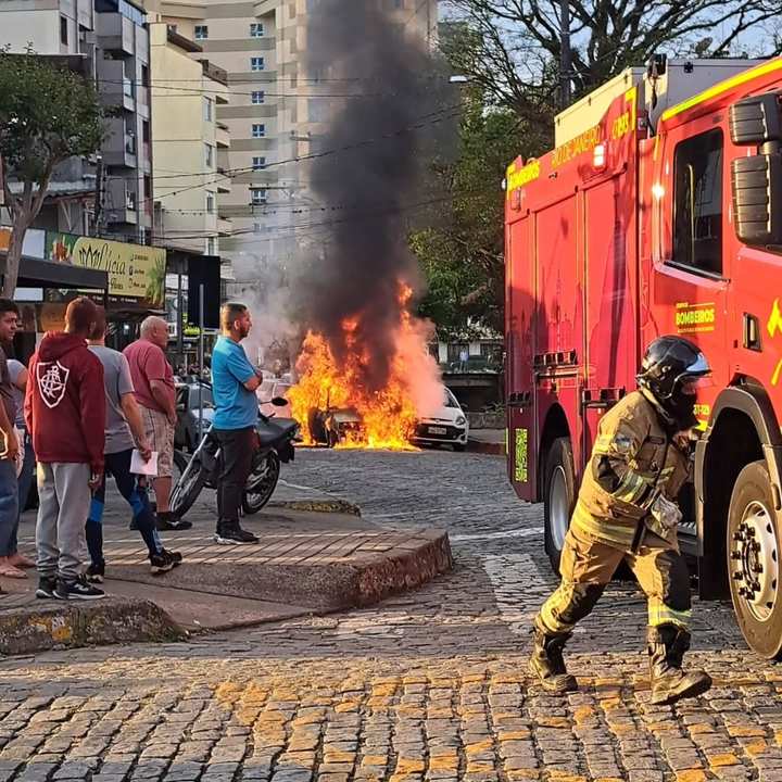 Carro em chamas com bombeiro e caminhão de bombeiros em cena, Nova Friburgo.