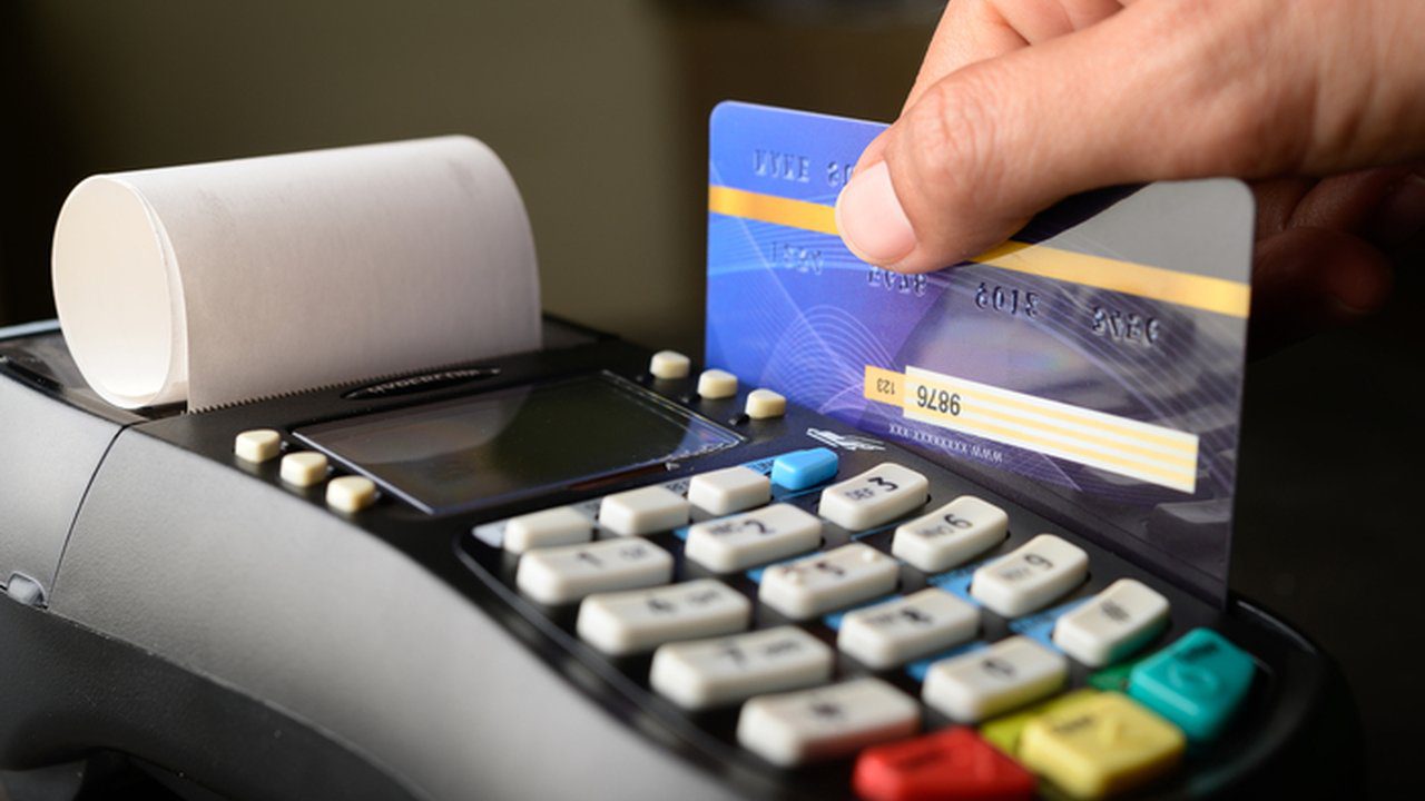 Cartão de crédito sendo usado em uma máquina de cartão para pagamento