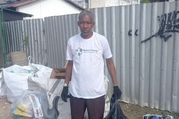 Catador de recicláveis em Nova Friburgo com vestimenta de reciclagem e sacola de lixo.