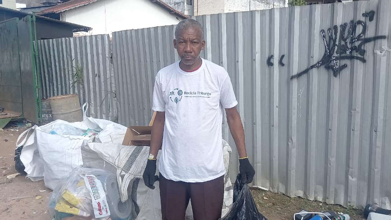Catador de recicláveis em Nova Friburgo com vestimenta de reciclagem e sacola de lixo.