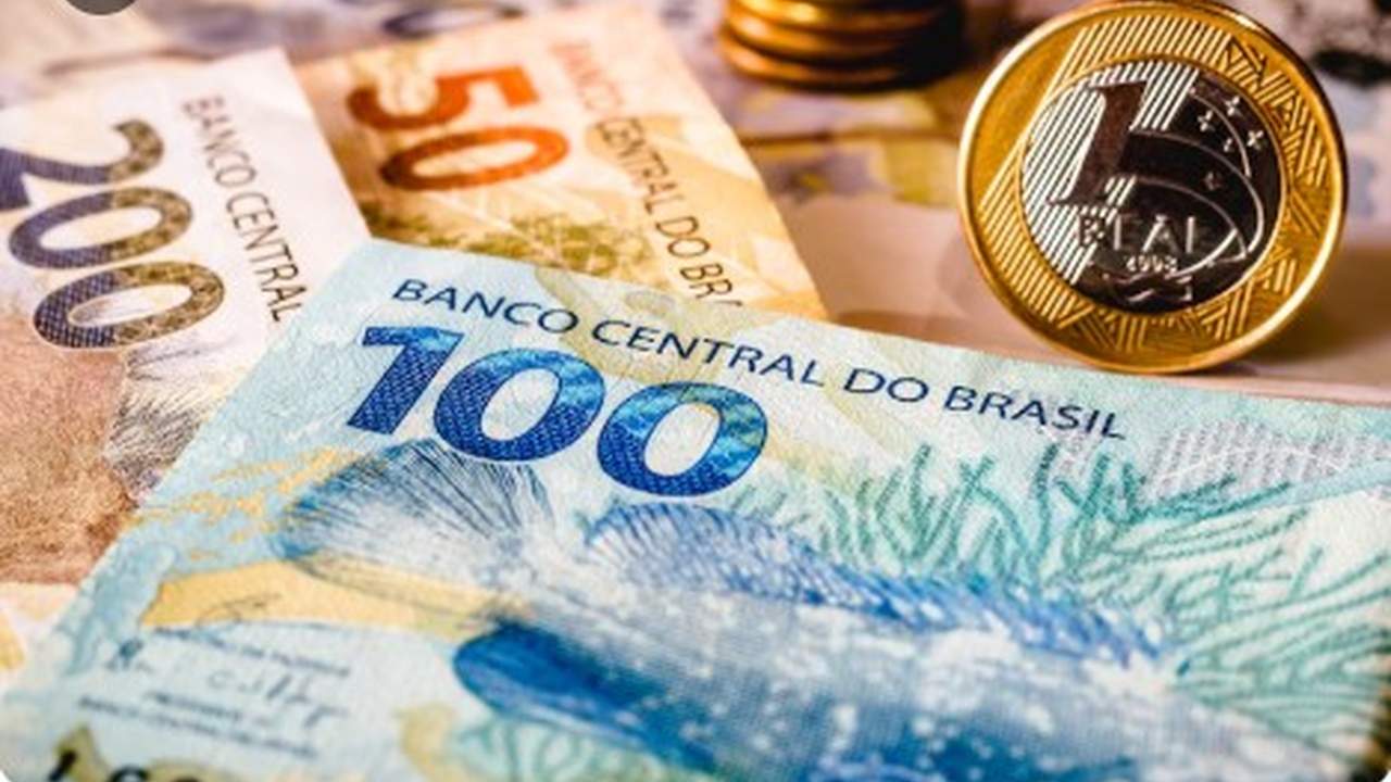 Cédulas de dinheiro do Brasil e moeda de 1 real em foco.