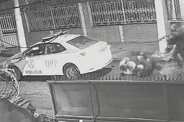 Cena de abordagem policial com carro da UPP e pessoas no chão.