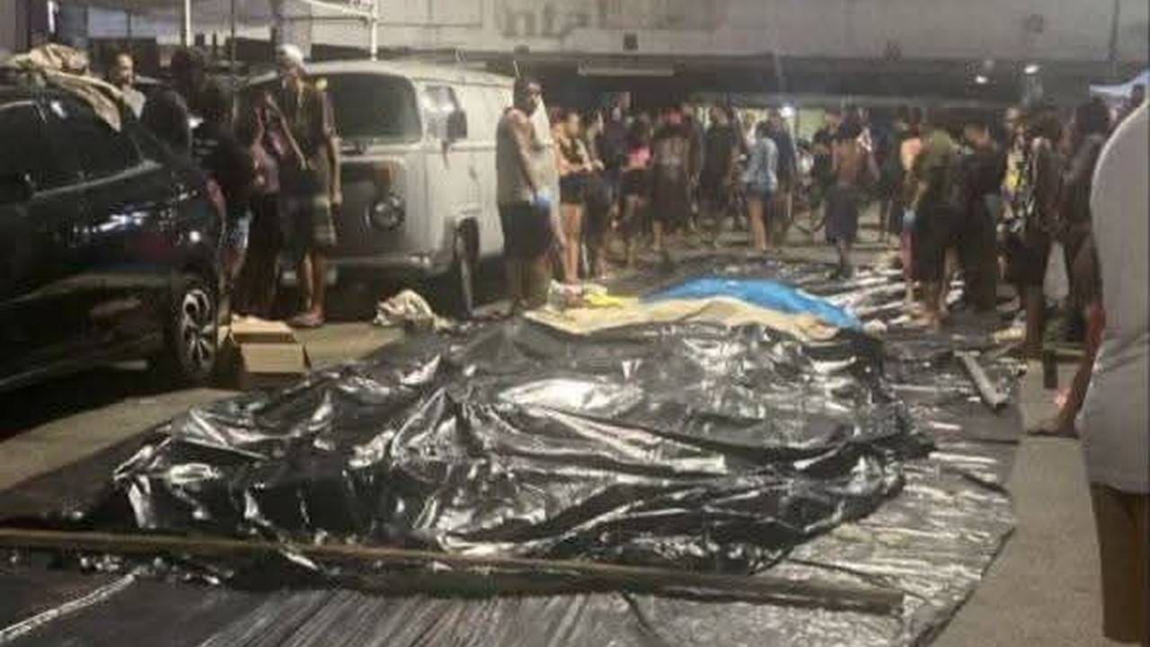 Cena no Complexo da Penha: corpos cobertos após operação policial no Rio de Janeiro, com pessoas ao redor.