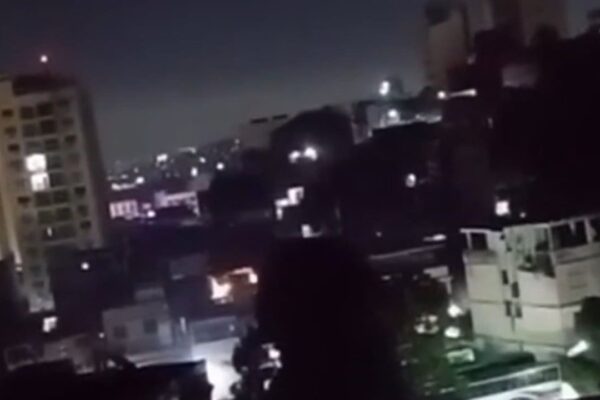 Cena noturna em Vigário Geral, Rio de Janeiro, com prédios e luzes.
