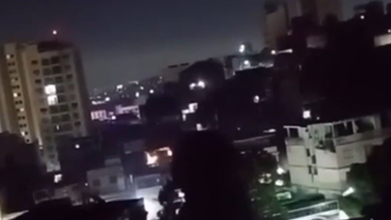 Cena noturna em Vigário Geral, Rio de Janeiro, com prédios e luzes.
