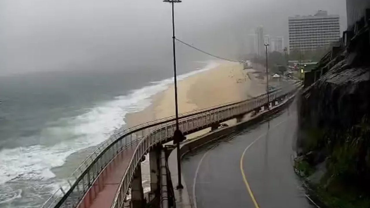 Ciclovia Tim Maia em dia chuvoso, com vista para a praia e edifícios ao fundo.