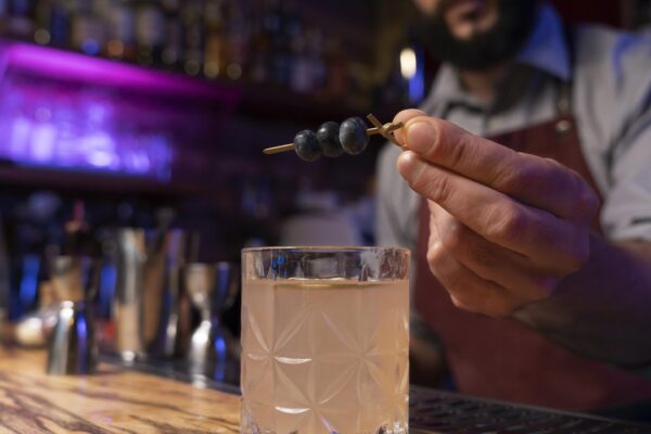 Cocktail sendo decorado com mirtilos. PF investiga bebidas adulteradas em SP.