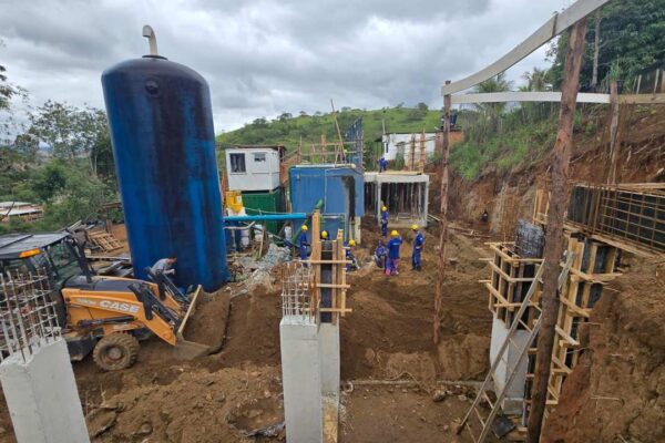 Construção de infraestrutura hídrica: Tanque azul e trabalhadores em obra.