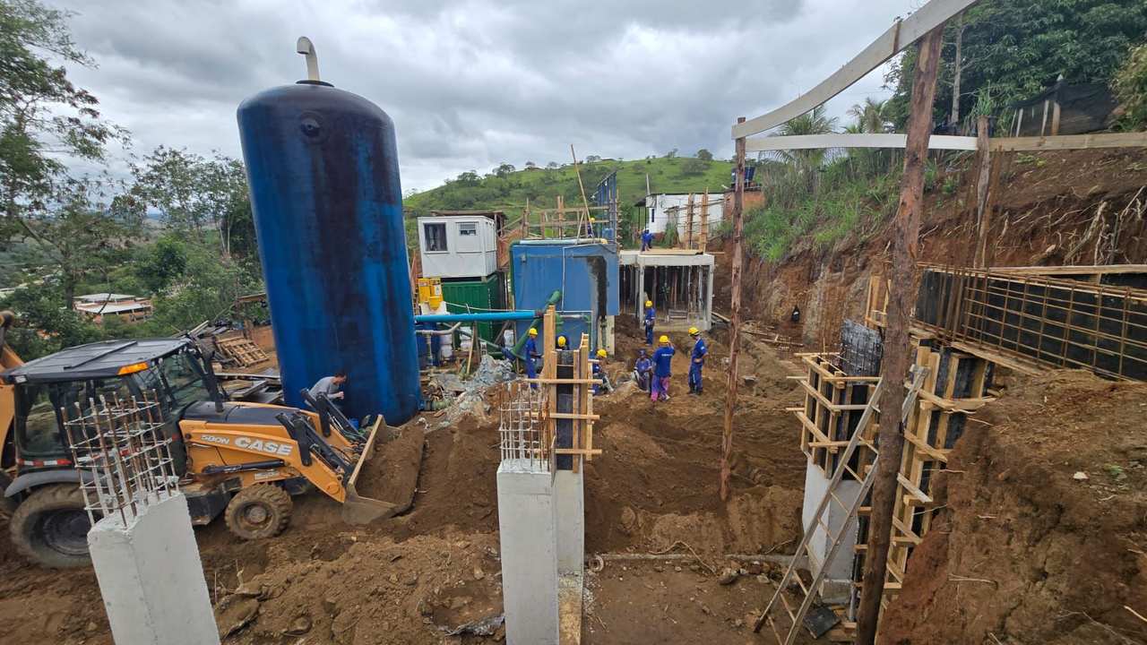Construção de infraestrutura hídrica: Tanque azul e trabalhadores em obra.