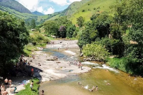 Crianças se divertem em cachoeira com águas claras e cristalinas