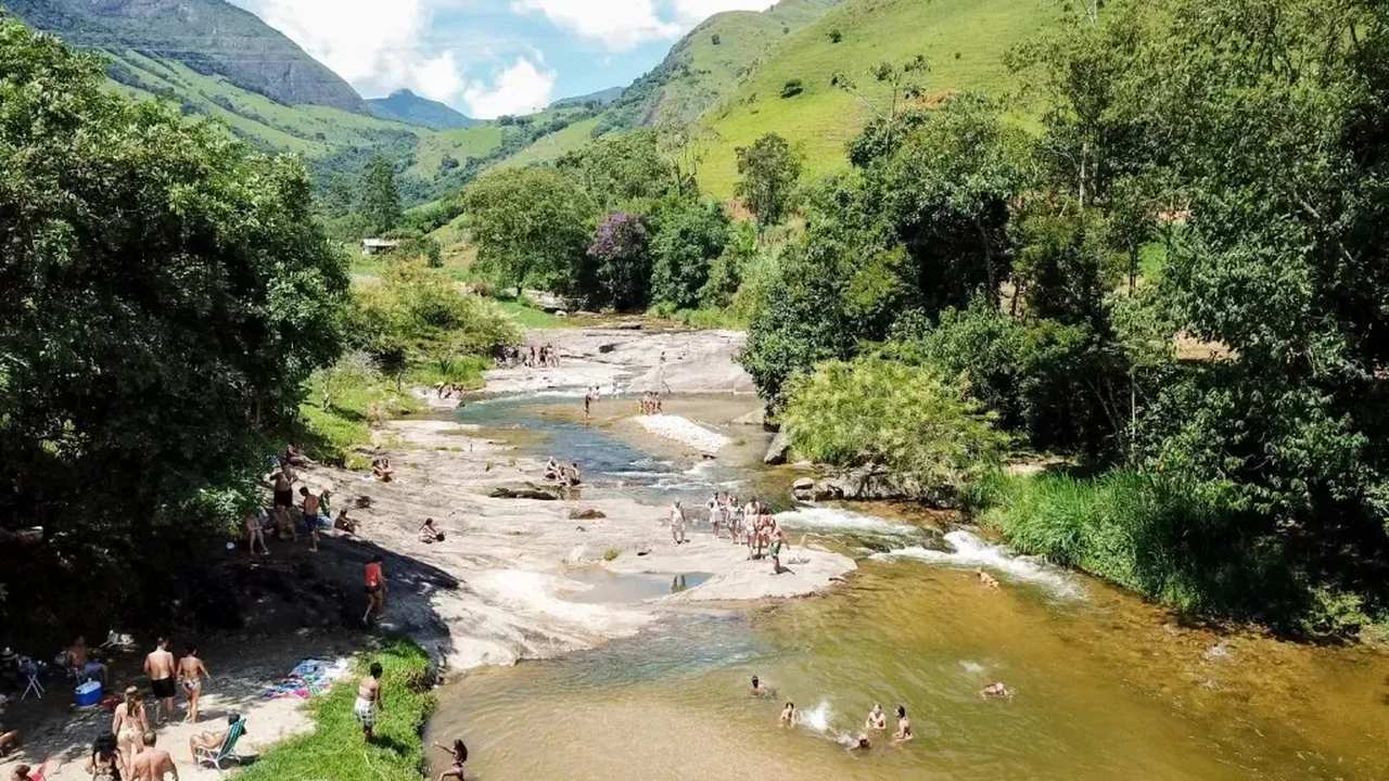 Crianças se divertem em cachoeira com águas claras e cristalinas
