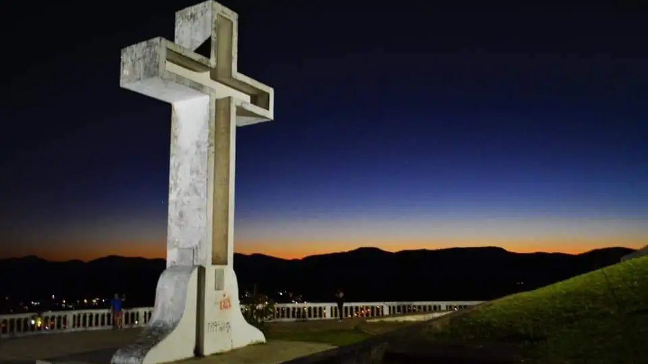 Cruzeiro no Mirante em Valença, com céu noturno e montanhas ao fundo.