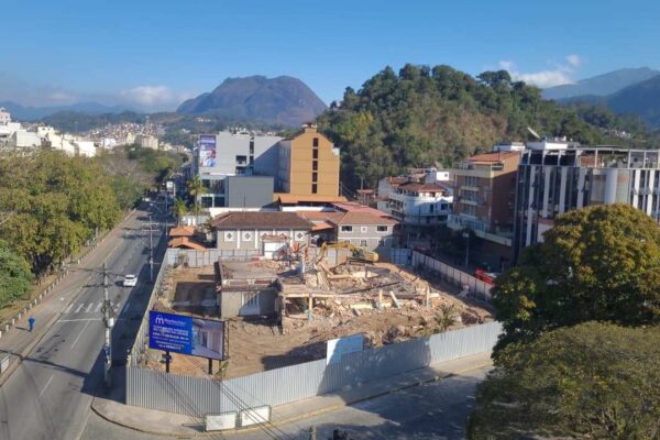 Demolição de estrutura no Clube do Xadrez, Nova Friburgo, com cidade ao fundo e montanhas.