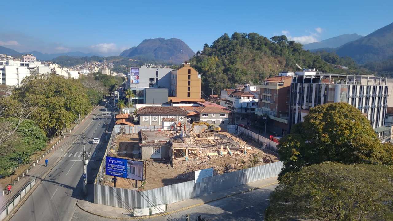 Demolição de estrutura no Clube do Xadrez, Nova Friburgo, com cidade ao fundo e montanhas.