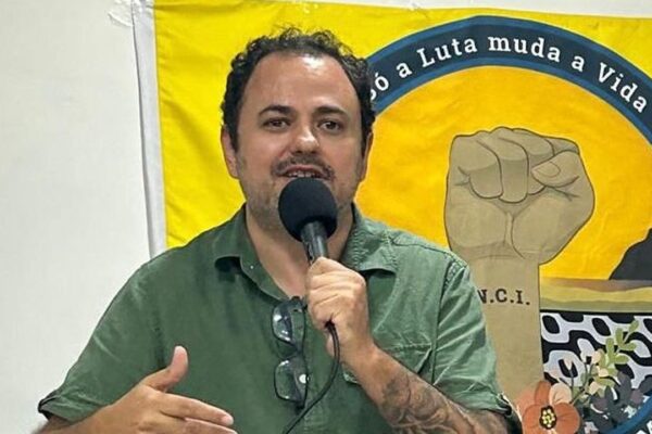 Deputado Glauber Braga discursando em frente a banner, possivelmente em visita a obra.