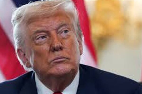 Donald Trump em foto, com bandeiras dos EUA ao fundo.