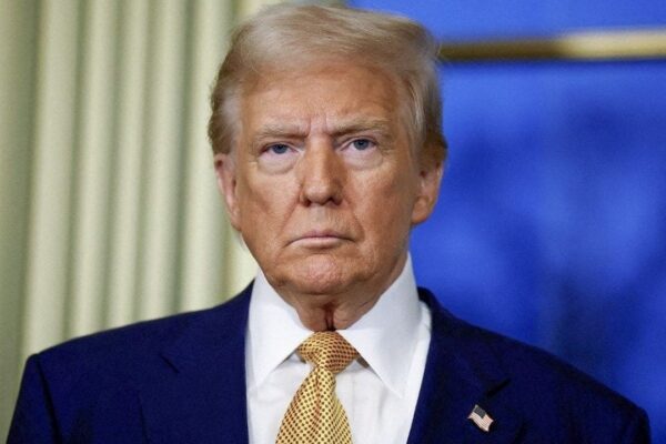 Donald Trump em um evento oficial, usando um terno azul e gravata amarela