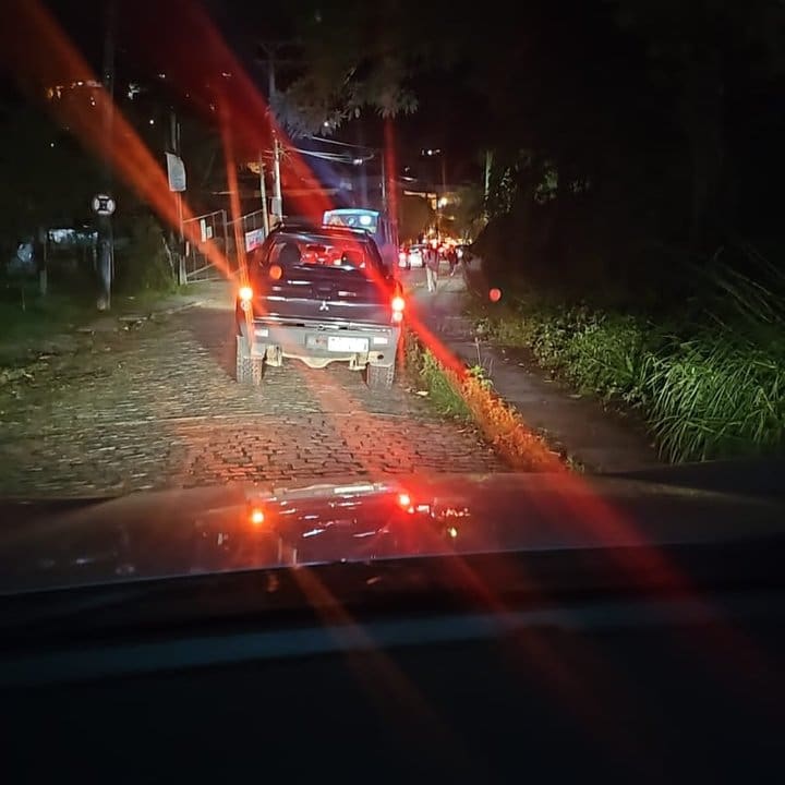 Engarrafamento noturno em Nova Friburgo com carro parado na via.