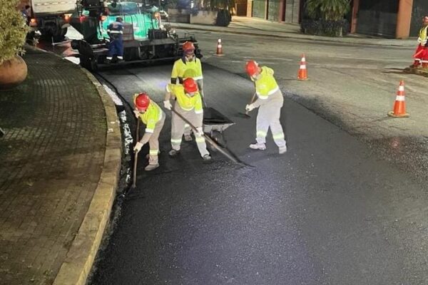 Equipe de obras realizando restauração em asfalto durante a noite.